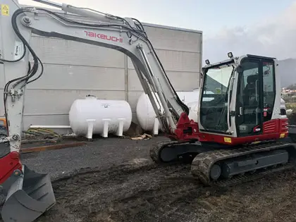 Retroexcavadora en operación de excavación en instalación industrial. Maquinaria con operador cualificado y mantenimiento al día.
