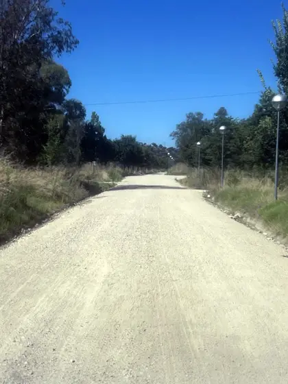 Camino rural con grava fina compactada y proteccion de cunetas.